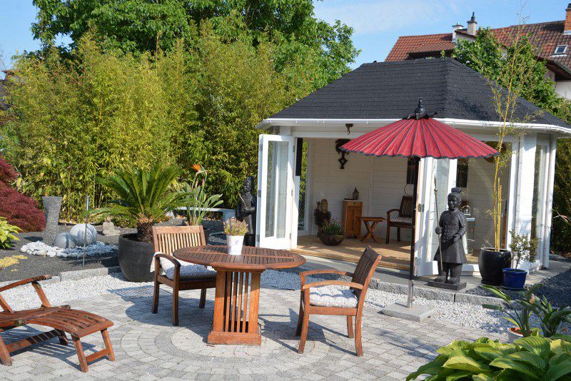 Der Zen-Garten und die Holzmöbel vor dem Gartenhaus komplettieren die friedliche Aura.