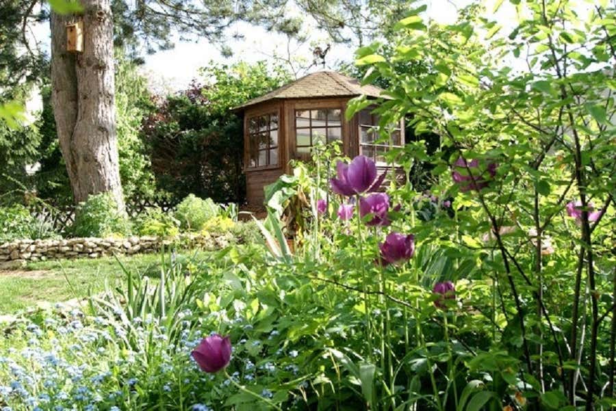 Das rustikale kleine Gartenhaus vollendet das malerische Ambiente des Gartens. 