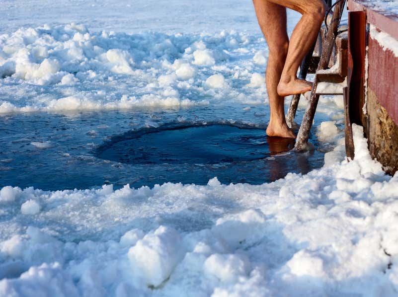 Mann steigt in ein Loch im zugefrorenen See 