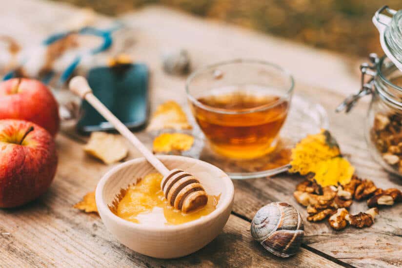 Honig in einer Schüssel mit Tee im Hintergrund