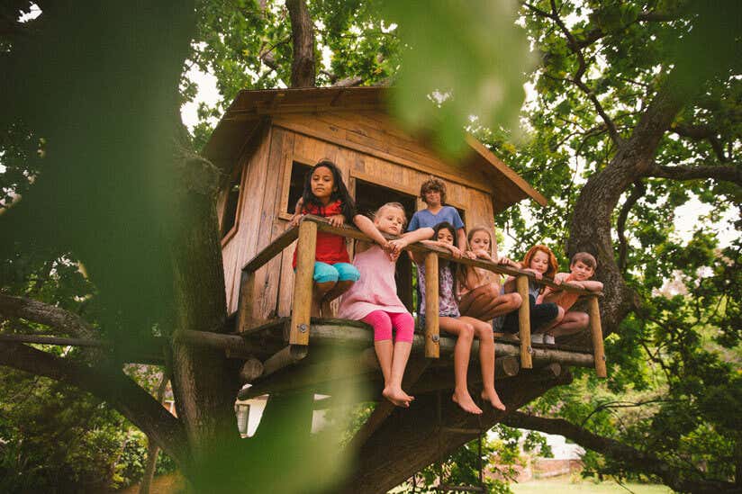 Kinder sitzen im Baumhaus