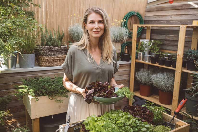 Frau an Pflanztisch in Garten